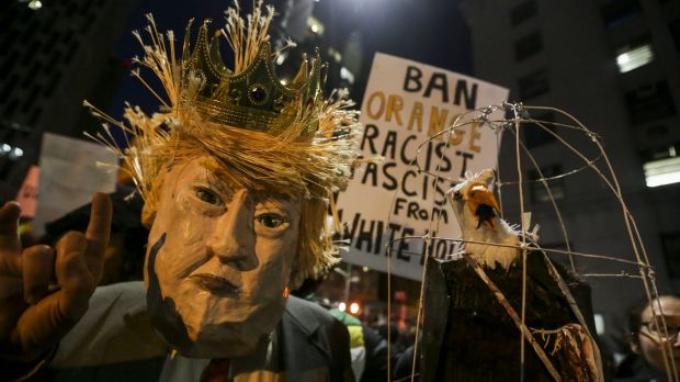 A demonstrator wearing a mask in the likeness of US President Donald Trump protests against his executive order in Los ...
