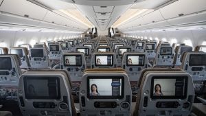 Entertainment monitors sit on the back of passenger seats in the economy class cabin of an Airbus SE A350 aircraft, ...