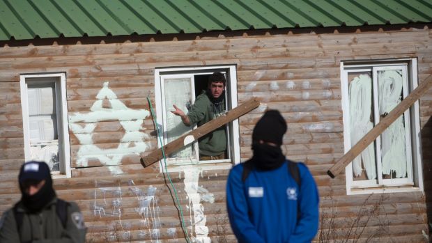 A settler barricaded inside a makeshift building in Amona surrounded by masked Israeli police.