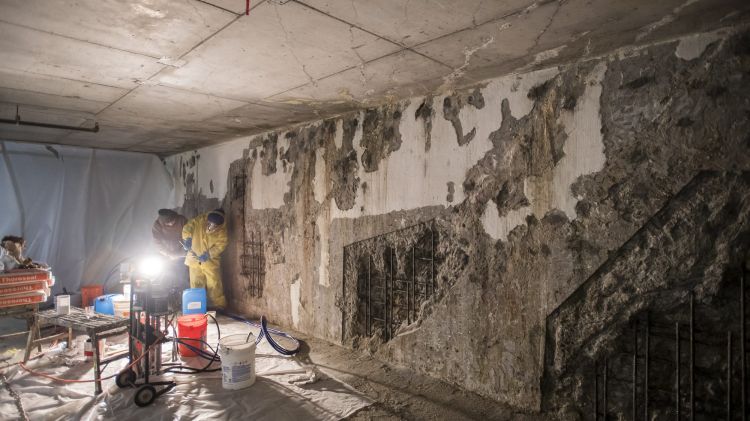 Workers repair crumbling walls that have been the result of leaking water in the garage of the Millennium Tower.