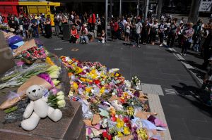 People lay flowers and sit quietly in Bourke Street Mall, Melbourne today.