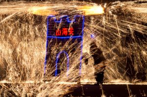A performer at the Great Wall Iron Sparks show turns a mechanism to spin molten iron and create sparks in Yanqing county ...