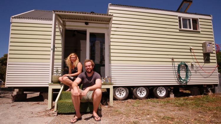 Ashleigh and Dan sit outside their tiny home.