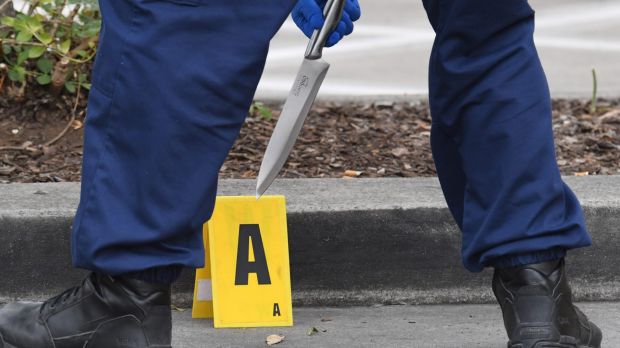 Police with one of the knives found at the scene.