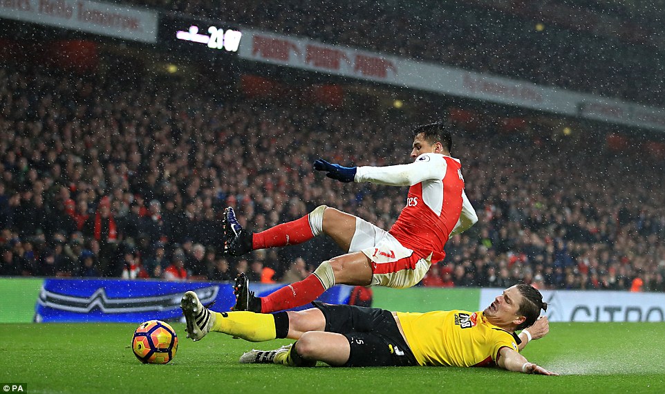 Sebastian Prodl flies through the back of Sanchez in an effort to win the ball, skidding along the wet turf at the Emirates