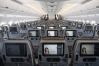 Entertainment monitors sit on the back of passenger seats in the economy class cabin of an Airbus SE A350 aircraft, ...