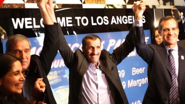 Ali Vayeghan, an Iranian citizen with a valid US, lifts his arms with his brother Houssein Vayghan, third from left, and ...