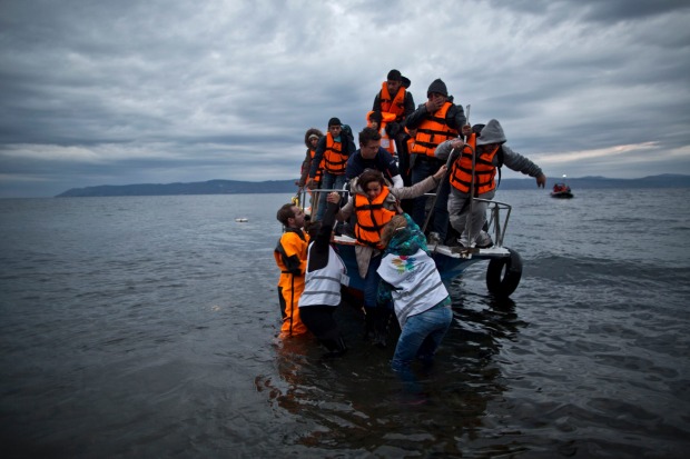Volunteers help Yazidi refugees disembark from a vessel as it arrives at the northeastern Greek island of Lesbos from ...