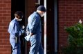 Forensics police walk past blood found on a pole outside units in St Albans.