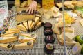A trader arranges cheeses in a chilled cabinet on a stall at Albert Cuyp street market in Amsterdam, Netherlands.