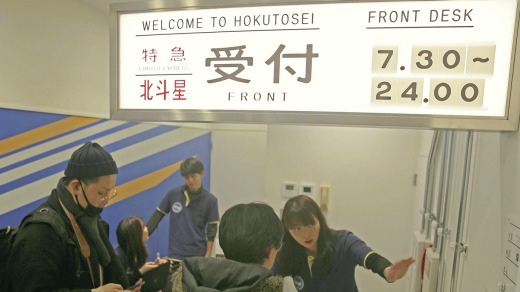 Visitors stops at the front desk at Train Hostel Hokutosei in Tokyo.
