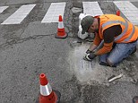 Jim Bachor scrapes away the cement to reveal his finished mosaic on a filled pothole in a Chicago street