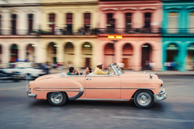 Tourists ride in a classic American car that serves as a taxi, in Havana, Cuba.