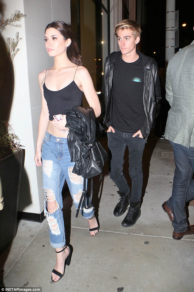 Chic: The girl also dressed on trend like Kaia does with strappy heels, ripped jeans and the staple black tank top, holding a black designer purse and leather jacket