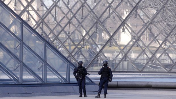 Police officers patrol at the pyramid outside the Louvre museum in Paris.