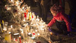 Une fillette allume une bougie en mémoire des victimes de la fusillade de Québec.