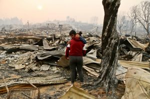 Juan Vega embraces his daughter where their home once stood after a wildfire in Santa Olga, Chile, Thursday, Jan. 26, ...