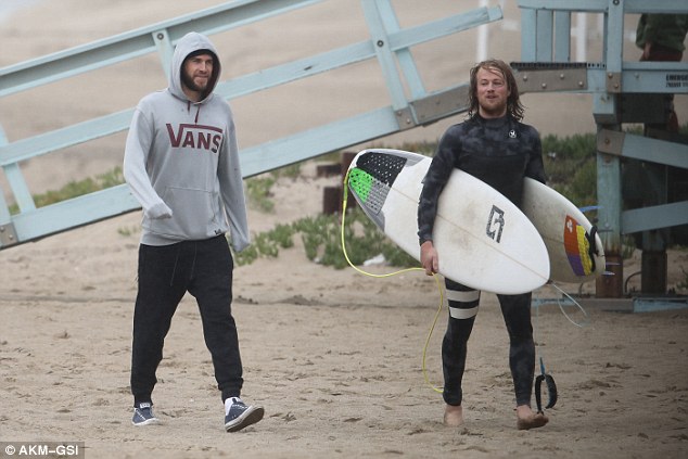 Too cold for a surf? Liam Hemsworth watches his friends catch waves at a Malibu beach but doesn't brave the winter water