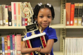 Anaya, 7, cradles her trophy after the handwriting contest. 