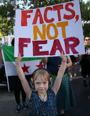 A child joins protests in Melbourne against Trump's travel ban affecting citizens from seven Muslim-majority countries.