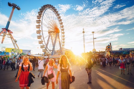 Munich, Germany - September 29, 2016:  Visitors Walking Through Oktoberfest Fairgrounds at sunset, Ferris Wheel in the ...