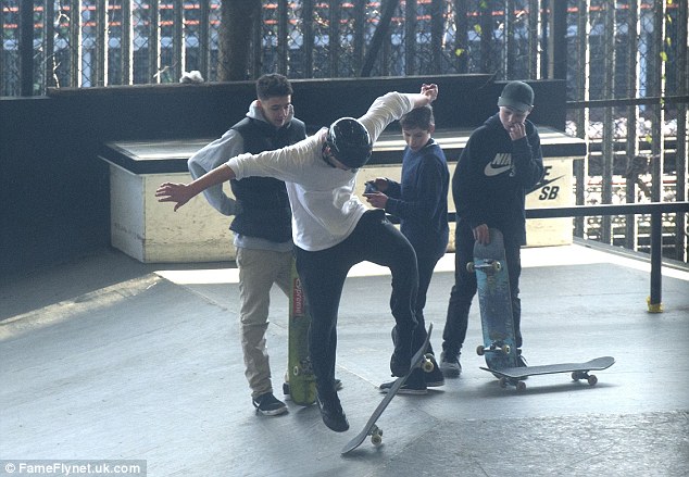 Brooklyn shows off his stuff and is pictured doing a kickflip as as his young friends watch on