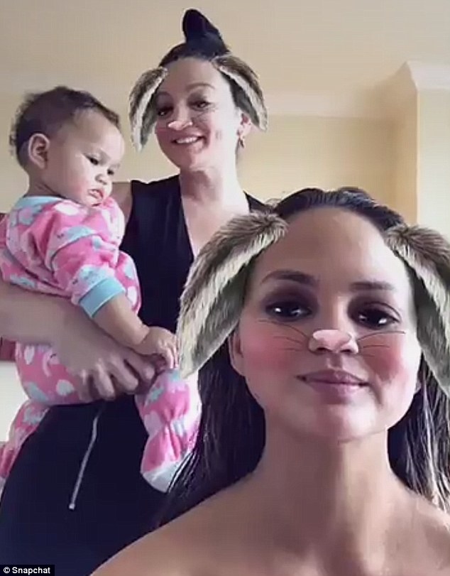 Multitasker: Meanwhile, her hairdresser Danielle stood behind her, cradling Teigen's baby Luna in one arm one hand and using her other hand to blow-dry the model's hair