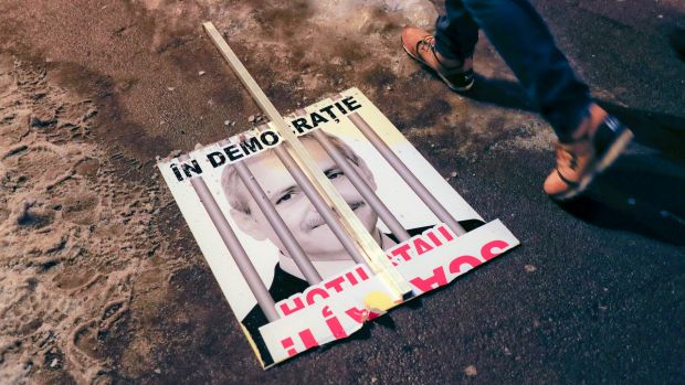 A broken poster depicting the leader of the ruling Social Democrat party Liviu Dragnea, which reads "In a democracy, ...