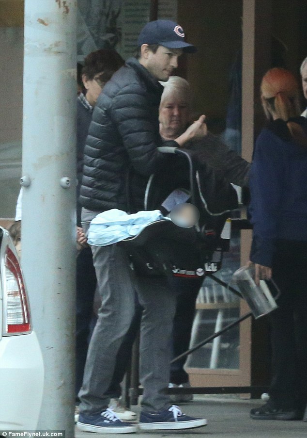 Doting dad: Ashton carried their two-month-old son Dimitri in a car seat as they exited the restaurant