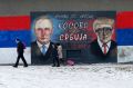 People walk by Serb nationalist graffiti depicting Russian President Vladimir Putin and US President Donald Trump in ...