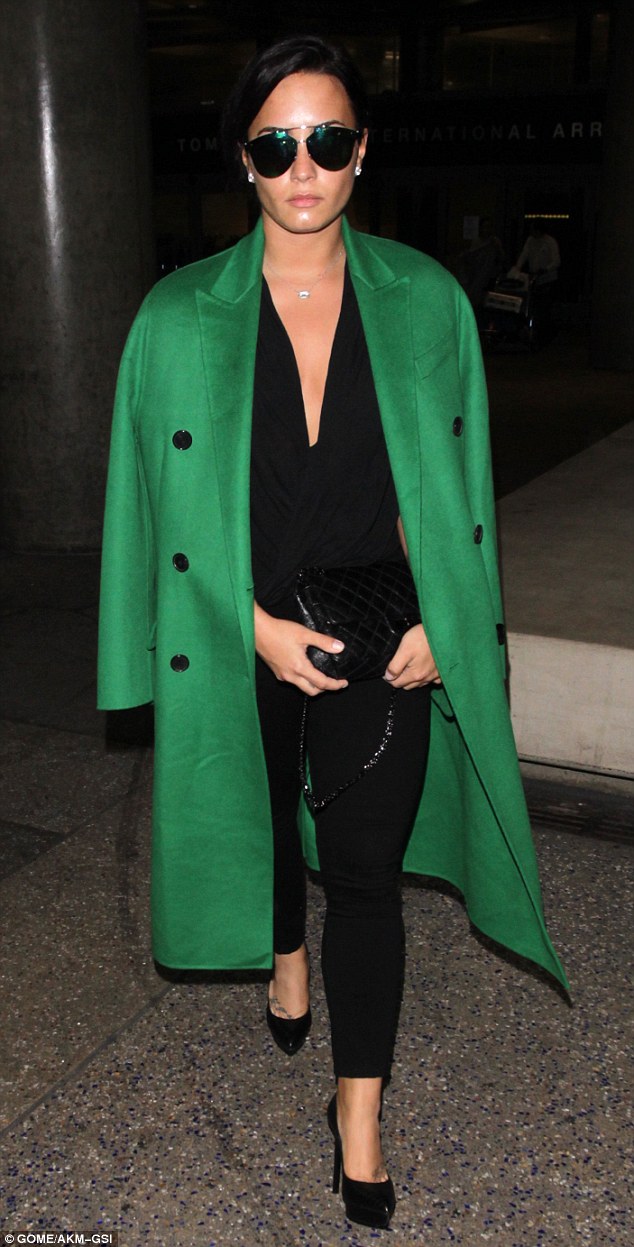 Not happy? Demi Lovato, 24, looked glum as she arrived back in Los Angeles from Dubai wearing an eye-catching bright green coat and sunglasses