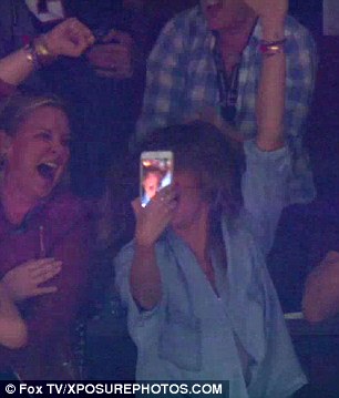 Partying it up: She proudly held up her mobile while celebrating with pals in the VIP box