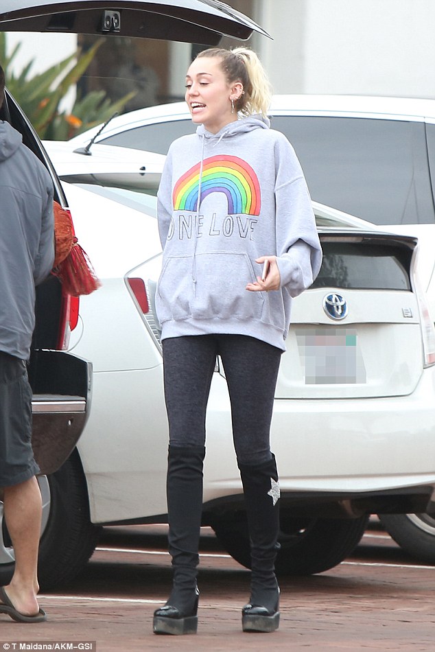 Peace, man: The pop star, 24, wore a gray hoodie with a rainbow and the words 'One Love' on the front and showed off her slim frame with a pair of black leggings and knee-high boots