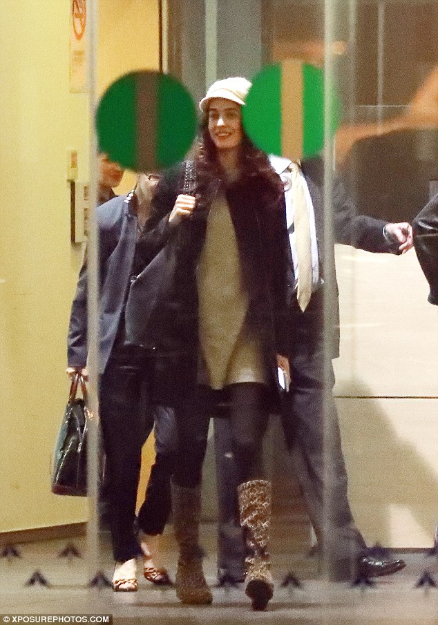 Beaming: Amal had a big smile on her face as she led the way out of the airport, wrapped up warm for the chilly weather