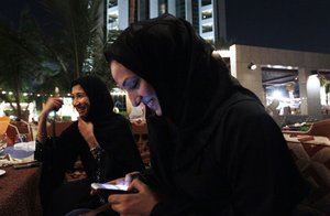 FILE - In this Nov. 11, 2010 file photo, Saudi woman with cellphones smoke tobacco from a waterpipe as they drink coffee in Jeddah, Saudi Arabia. Saudi King Abdullah has given the kingdom's women the right to vote for first time in nationwide local elections, due in 2015. The king said in an annual speech on Sunday before his advisory assembly, or Shura Council, that Saudi women will be able to run and cast ballots in the 2015 municipal elections.