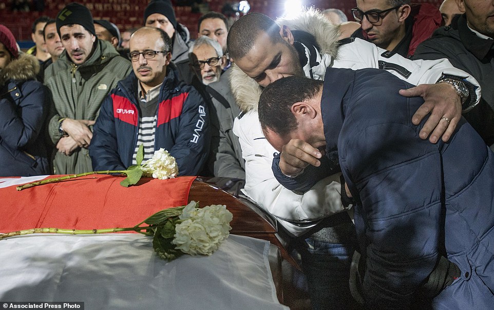 A man weeps next to the caskets of three of the six victims of the Quebec City mosque shooting during funeral services at the Maurice-Richard Arena on Thursday in Montreal