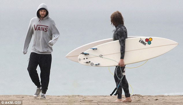 Beach bums: Liam walked with his surfer pal as they explored the ocean scenery