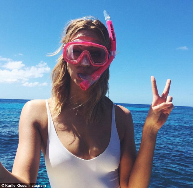 Peace out: The Victoria's Secret model sports an elegant, white one piece swimsuit and a cute bright,  pink scuba diving mask, while holding up a peace sign