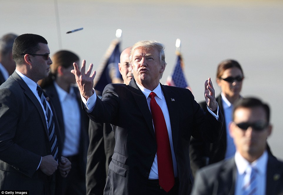 President Donald Trump tosses a sharpie pen that he was using for autographs back to the group that greeted him after arriving on Air Force One