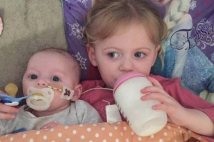 Baby Evelie, here with her big sister Mila-Beau, is defying the odds.