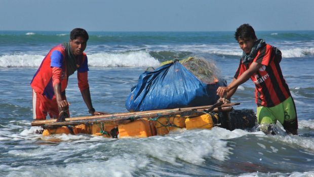 Rohingya fishermen pull a raft made of empty plastic containers along the coastline of the Bay of Bengal in Maungdaw, ...