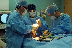 Joseph Slakey, removes a right tibial tumor from a young boy's leg during surgery aboard the Military Sealift Command hospital ship USNS Comfort (T-AH 20).