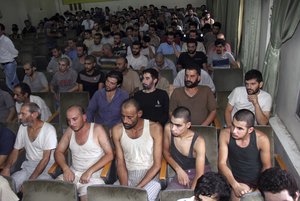 FILE - In this Saturday, Sept. 1, 2012, file photo, Syrian prisoners sit in a courtroom before their release in Damascus, Syria.