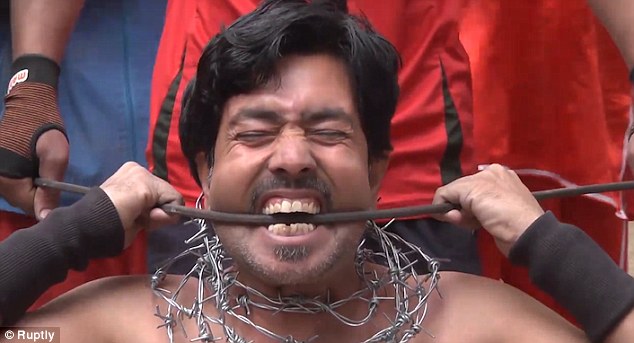 Stunt school: A man bends a metal bar in his mouth in Pakistan