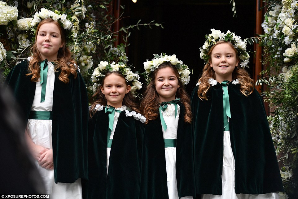 The adorable flower girls whore white dresses trimmed with green ribbons and kept warm under heavy velvet capes 