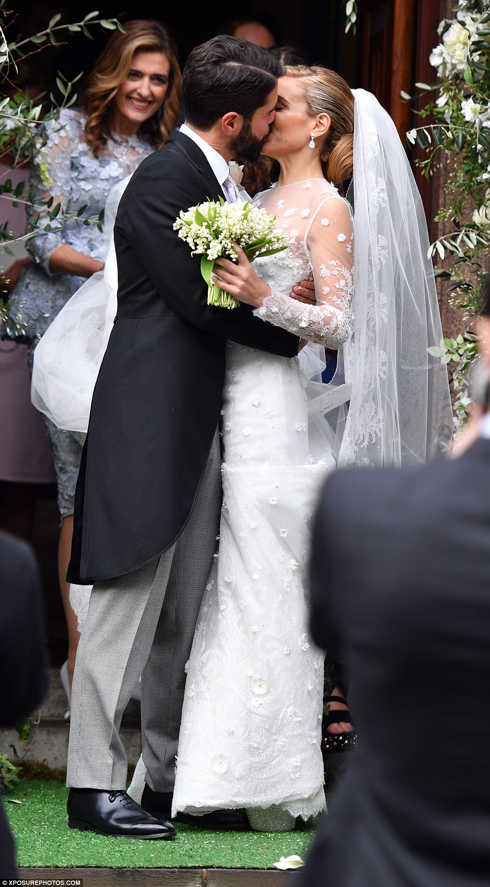 They newlyweds steal a kiss outside the church, much to the delight of onlookers 