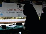 A young woman walks past a banner against female genital mutilation ©SIMON MAINA (AFP/File)