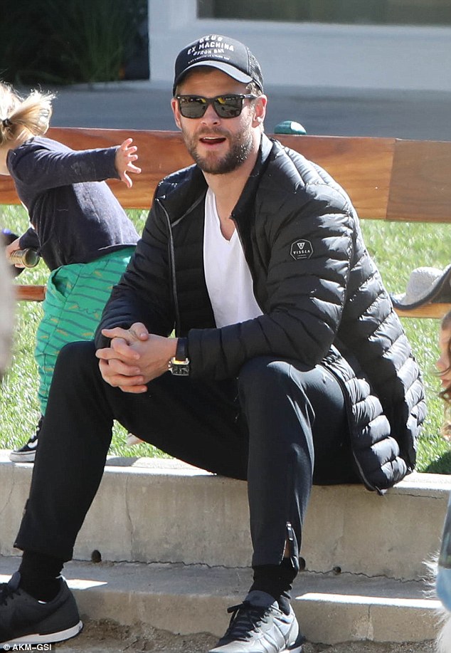 Dad's in charge! Hemsworth took a breather as his son scampered nearby 