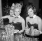 FILE - In this Jan. 15, 1963 file photo, Playboy Bunnies Elka Hellmann, from left, Monica Schaller and Sabrina Scharf serve drinks at New York's Playboy Club. The tightly corseted Playboy Bunnies, with rabbit tails and ears, will soon be back in business in New York City. Three decades after the original Playboy Club closed in Manhattan, a new club will debut later this year in a hotel a few blocks from Times Square. (AP Photo/John Lent, File)
