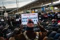 A group of Muslim men pray while supporters hold up signs during an interfaith prayer and rally against the ban at John ...